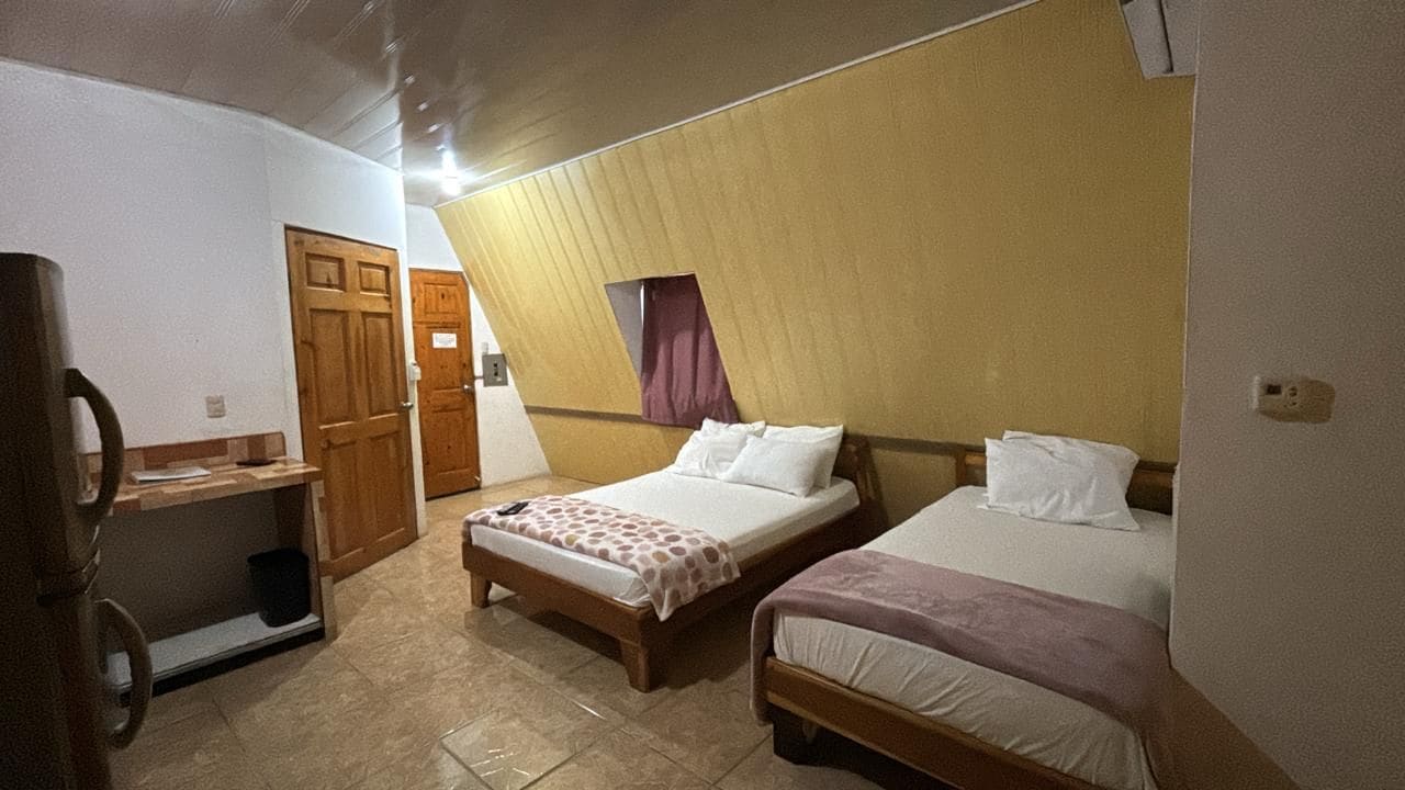 A hotel room with two beds, a desk, and a wardrobe.