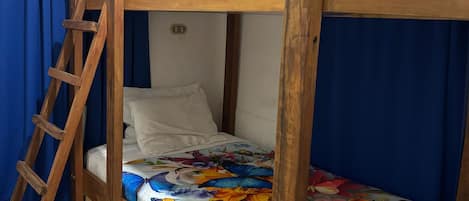 Una cama nido con escalera de madera, colcha estampada de flores y cortinas azules.