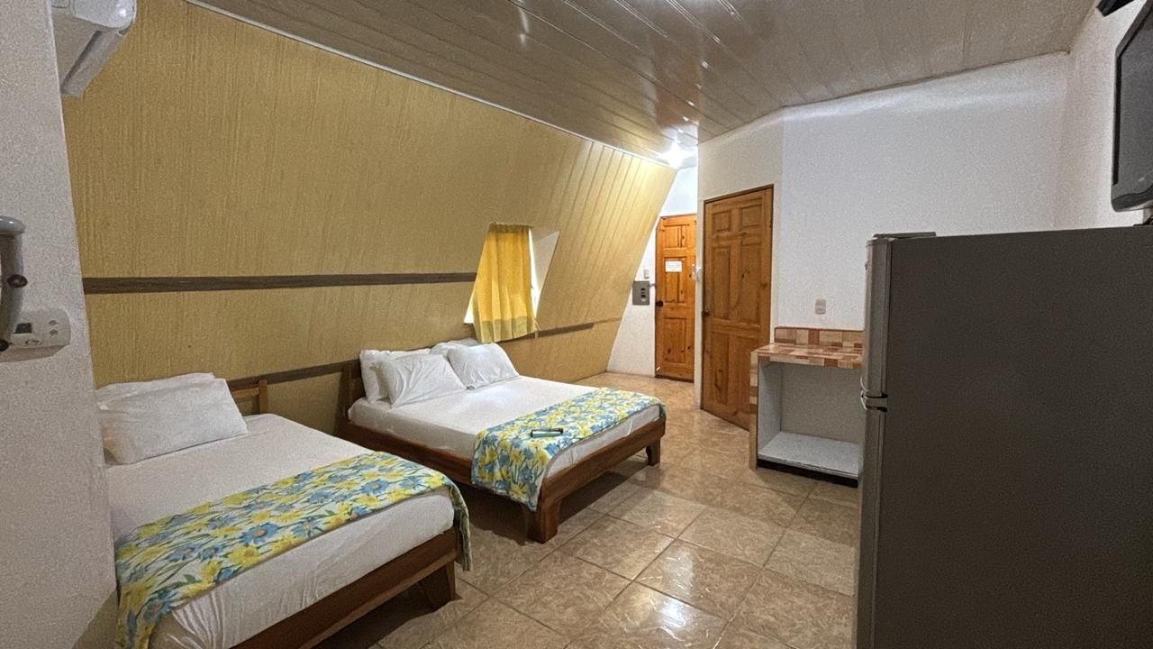 A hotel room with two beds, a refrigerator, and a wooden door.