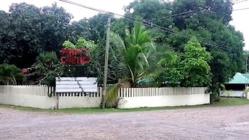 A sign for a hotel with a white fence and lush greenery in the background.