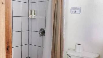 A bathroom with a shower, toilet, and tiled floor.