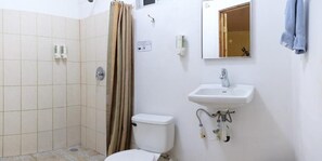 Une salle de bain équipée de toilettes, d’un lavabo, d’une douche et d’un miroir.