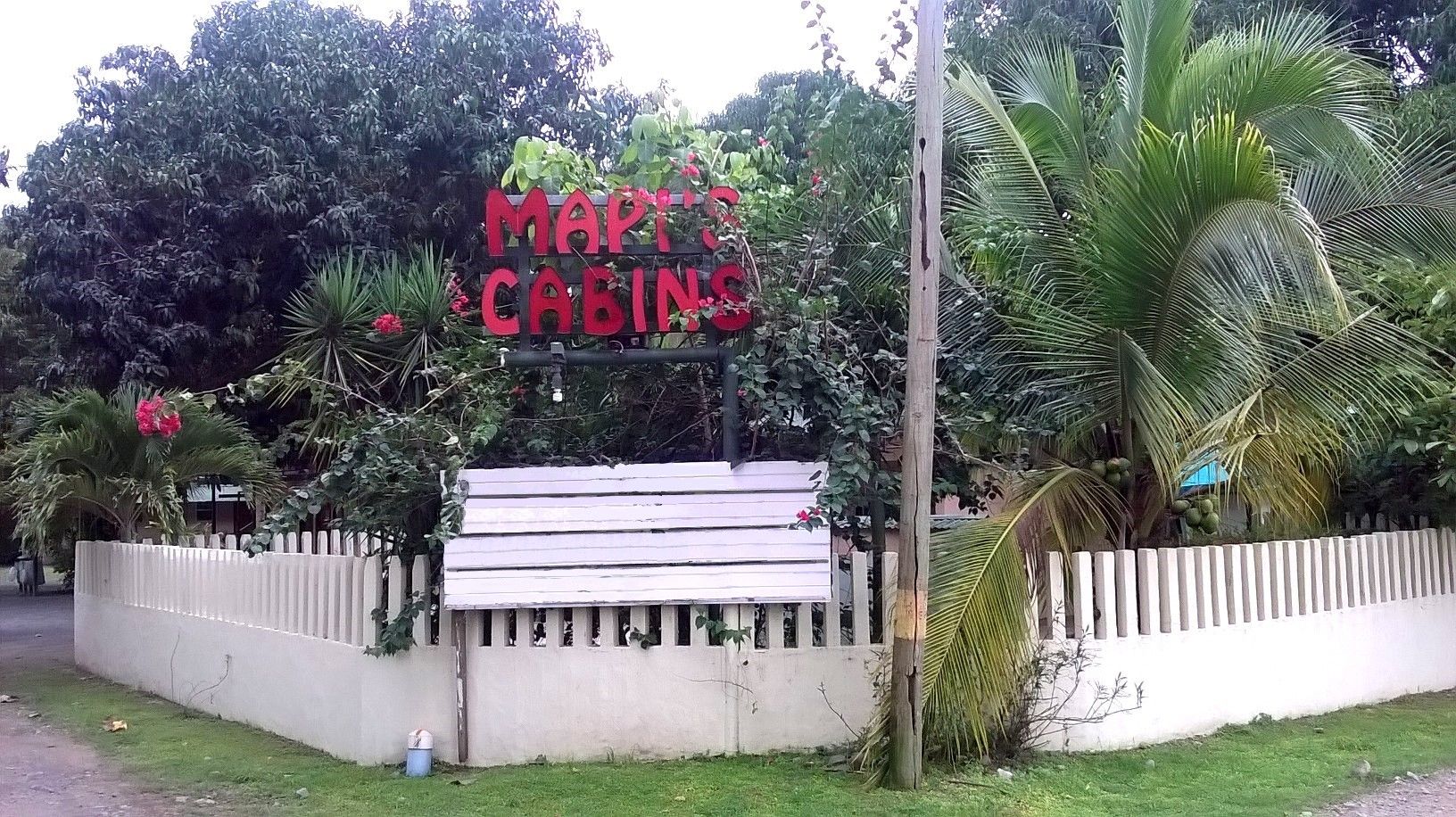 A sign for 'MART'S CABINS' with a white picket fence and lush greenery.