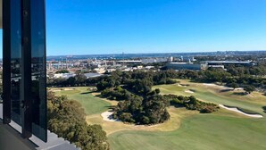 Blick auf einen Golfplatz mit einer Stadtlandschaft im Hintergrund.