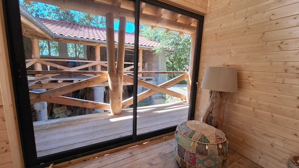A wooden cabin with a large sliding glass door leading to a wooden deck.