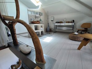 A modern kitchen with a skylight, a dining area with a wooden table, and a seating area with a woven pouf.