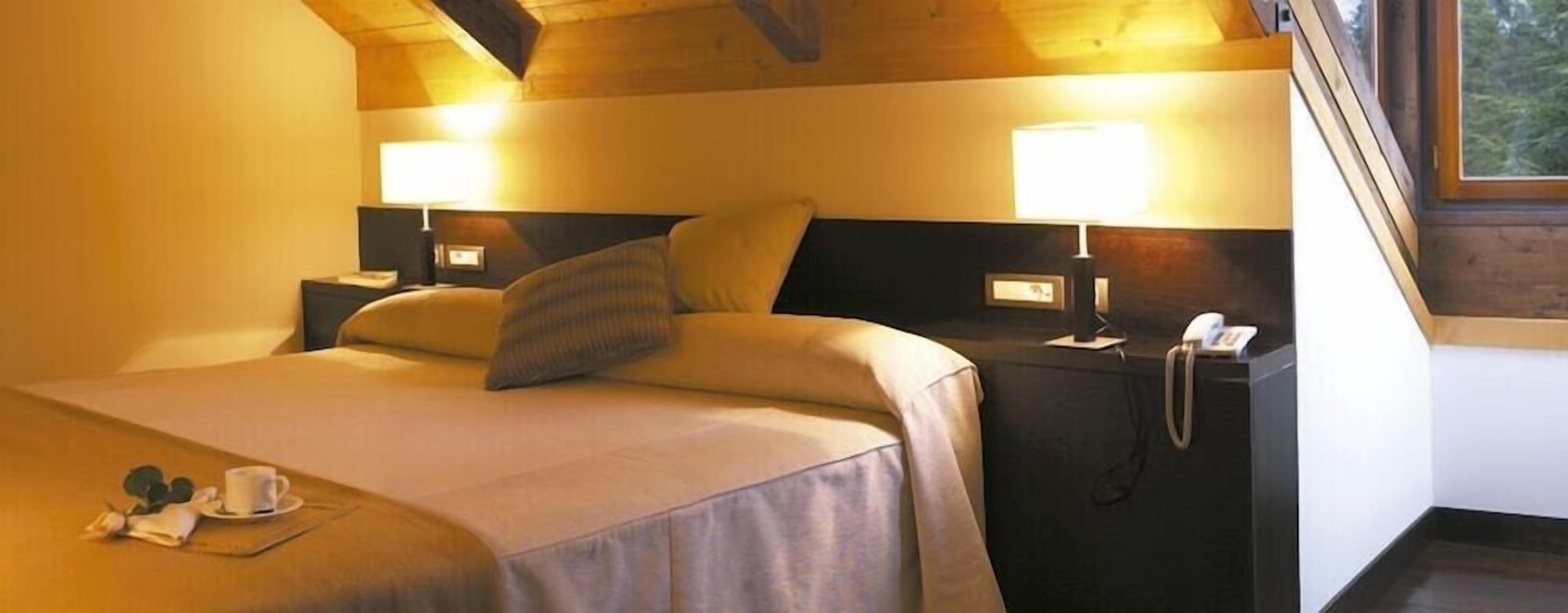 Una habitació d'hotel amb llit, taules de nit, làmpada i telèfon.