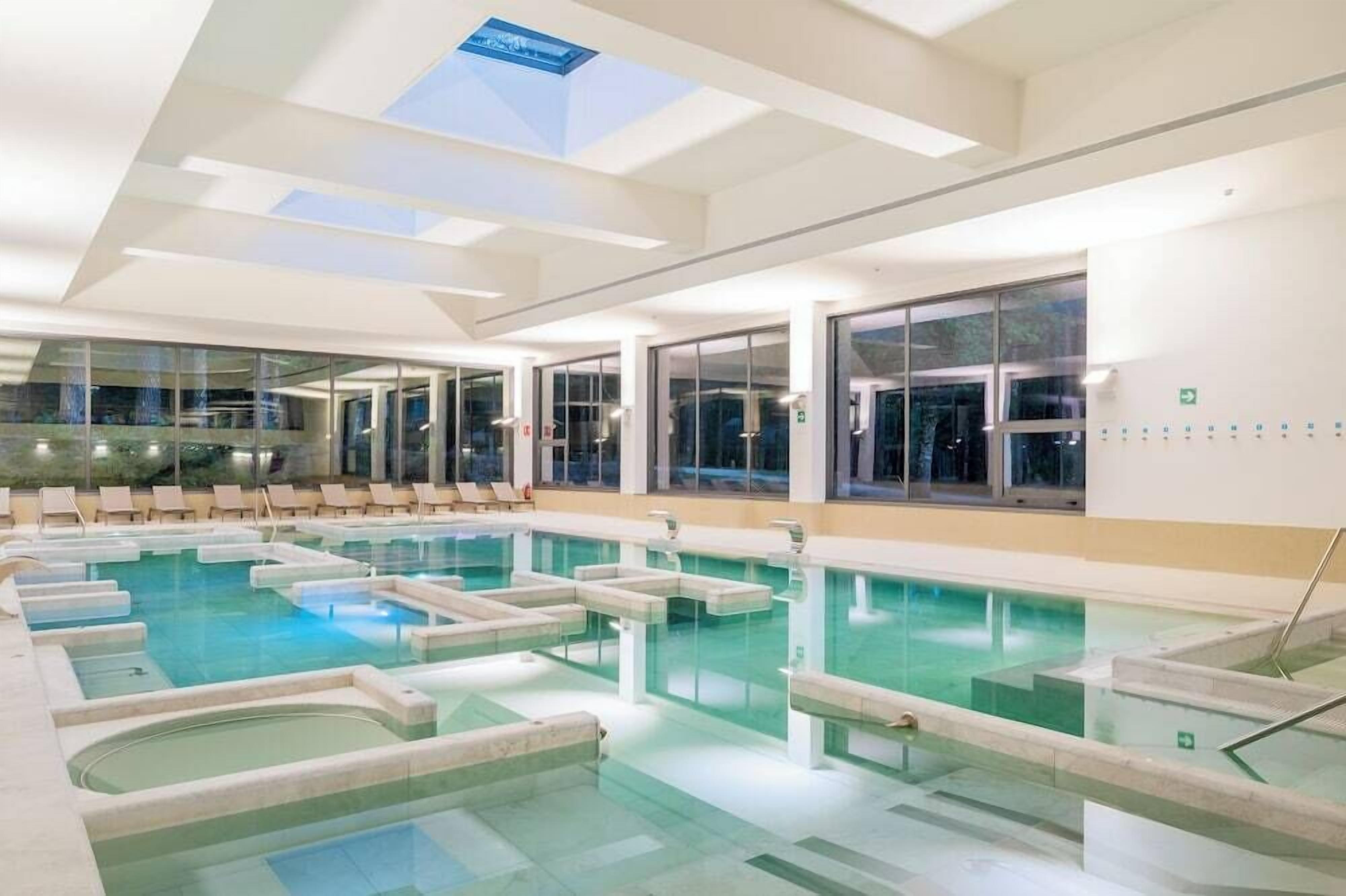Una amplia piscina cubierta con varias pistas y una claraboya arriba.