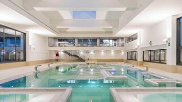 Una gran piscina interior amb diverses línies, una escala que mena a un nivell superior i un rellotge a la paret.