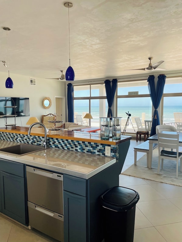 A modern kitchen with a large island, a dining area with a view, and a ceiling fan.