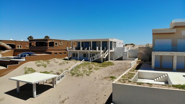 Un resort moderno con varias edificaciones, mobiliario exterior y un paisaje arenoso.