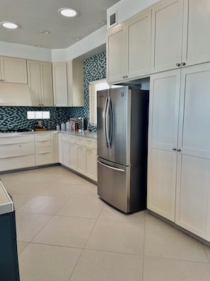 A modern kitchen with white cabinets, a stainless steel refrigerator, and a tiled backsplash. - Silver Seas – Oceanfront Home in Santo Tomás, Mexico (Playa Santo Tomás)
