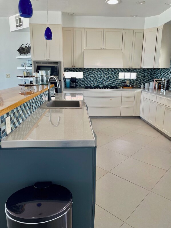 A modern kitchen with a central island, a sink, and a stove. - Silver Seas – Oceanfront Home in Santo Tomás, Mexico (Playa Santo Tomás)