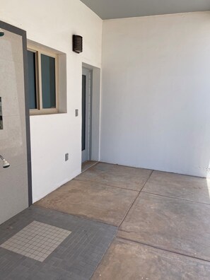 A corridor with a door, a window, and a wall-mounted light fixture. - Silver Seas – Oceanfront Home in Santo Tomás, Mexico (Playa Santo Tomás)