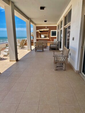 A covered outdoor area with tiled flooring, wooden furniture, and a view of the ocean. - Silver Seas – Oceanfront Home in Santo Tomás, Mexico (Playa Santo Tomás)