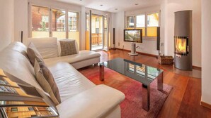 Un salon moderne avec un canapé, une table basse en verre, une cheminée et un téléviseur.
