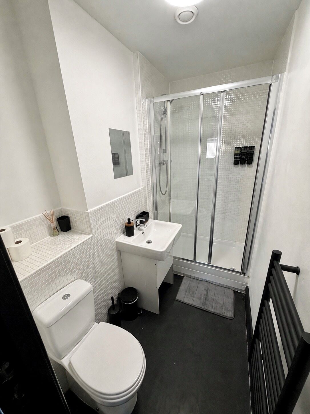A modern bathroom with a toilet, sink, and glass-enclosed shower.