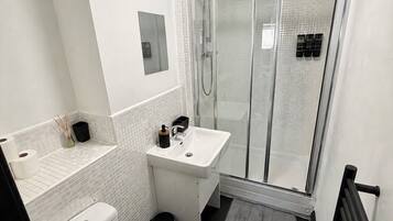 A modern bathroom with a toilet, sink, and glass-enclosed shower.