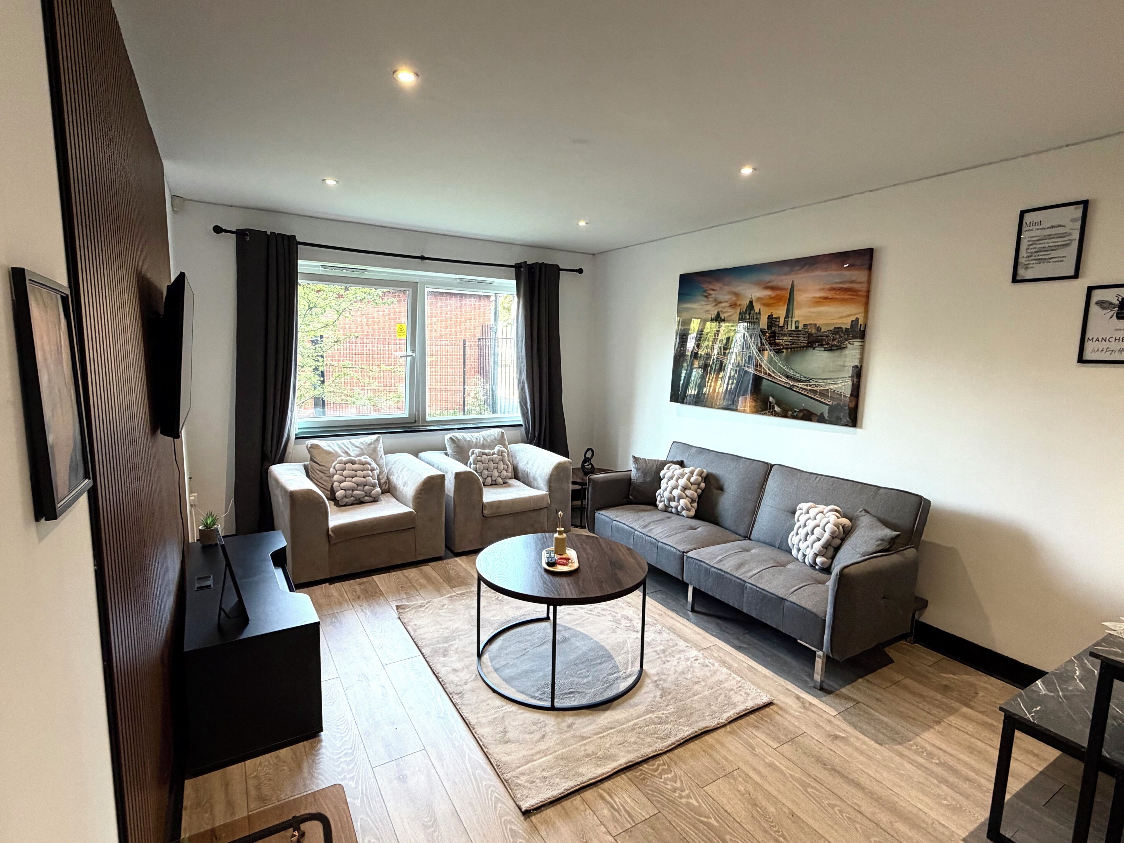A modern living room with a sofa set, a coffee table, and a painting of a cityscape.