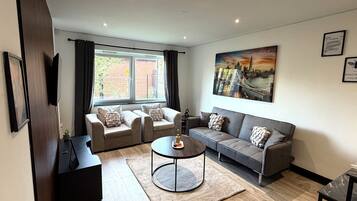 A modern living room with a sofa set, a coffee table, and a painting of a cityscape.