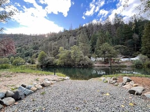 A natural landscape with a lake, surrounded by trees and a rocky foreground.
