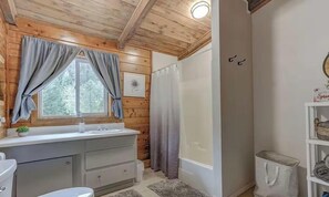 A bathroom with wooden paneling, a sink, a toilet, and a shower curtain.
