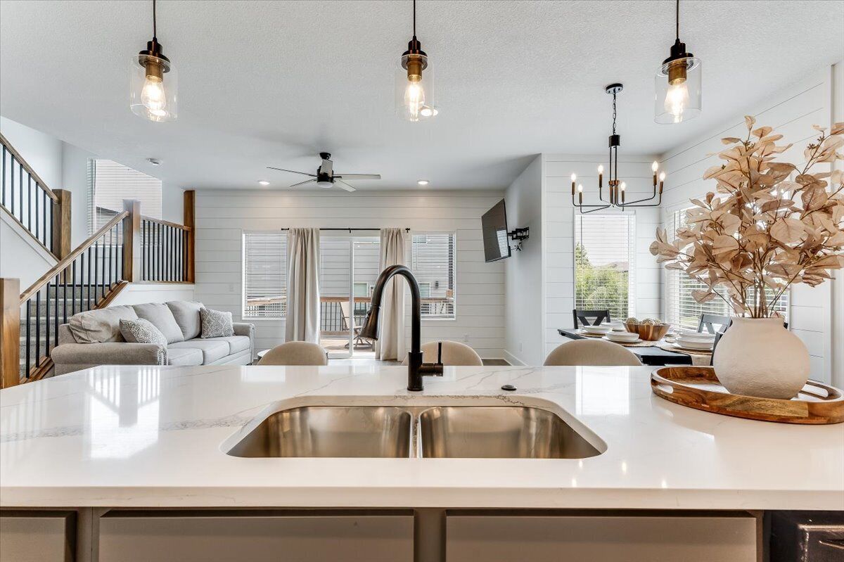 A modern kitchen with a central island, stainless steel sink, and pendant lighting.
