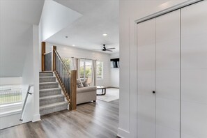 A spacious room with a staircase leading to an upper level, a sofa, and a view through a window.
