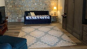 Quarto com parede de pedra, cama com colcha estampada, um armário de madeira e um tapete estampado.
