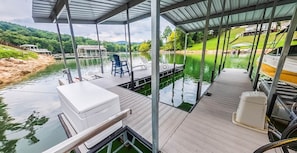 A covered dock with a boat, a table, and a chair. - Cove Manor - Lake front with Dock (Union County)