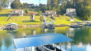 Um píer à beira do lago com área de estar coberta, um barco e uma rampa para lançamento de barcos.