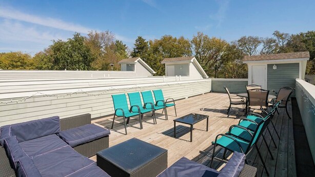 A rooftop deck with outdoor seating, including lounge chairs and a table, surrounded by trees and a clear sky. - #3B, Rooftop Deck, Pool Table, 3 mi to Broadway (Nashville)