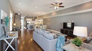 A modern living room with a sofa, TV, and dining area. - #3B, Rooftop Deck, Pool Table, 3 mi to Broadway (Nashville)