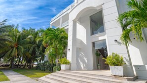 Ein modernes Gebäude mit heller Fassade, großen Fenstern und einem gepflegten Garten mit Palmen.