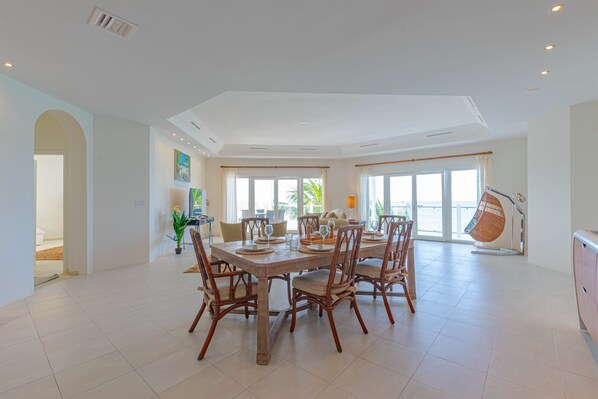 Uma sala de jantar ampla com pé direito alto, grandes janelas e vista para o exterior.