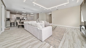 A modern living room with a sofa, a coffee table, and a rug. - 7BD Home w Pool Game Room Near Parks (ON56) (Championsgate)