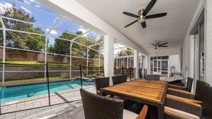 An outdoor patio with a pool, wicker furniture, and ceiling fans. - 7BD Home w Pool Game Room Near Parks (ON56) (Championsgate)
