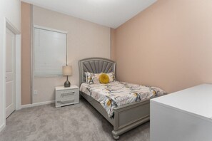 Ein Schlafzimmer mit einem Bett, einem Nachttisch, einer Lampe und einer Kommode.