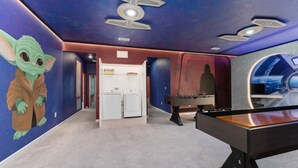 Ett rum med Star Wars-tema, inklusive en väggmålning med en karaktär, ett fotbollsspel och en tvättmaskin.