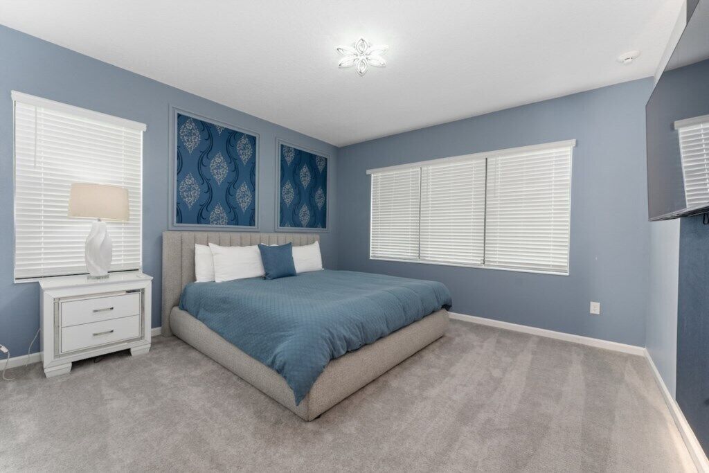A bedroom with a bed, nightstands, a lamp, and decorative wall art.