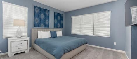 A bedroom with a bed, nightstands, a lamp, and decorative wall art.