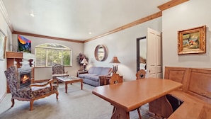 A living room with a fireplace, seating, a dining table, and a painting on the wall. - 2BR 2BA Midway villa with full kitchen, pool view, and resort amenities. (Midway)