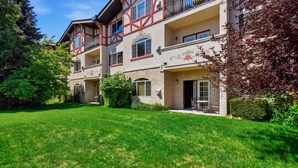 A two-story building with a balcony, a well-maintained lawn, and a clear sky. - 2BR 2BA Midway villa with full kitchen, pool view, and resort amenities. (Midway)
