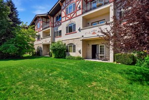 A two-story building with a balcony, a well-maintained lawn, and a clear sky. - 2BR 2BA Midway villa with full kitchen, pool view, and resort amenities. (Midway)