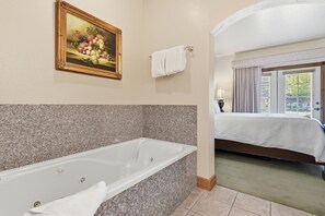 A hotel bathroom with a bathtub, a painting of fruit, and a bed with a window. - 2BR 2BA Midway villa with full kitchen, pool view, and resort amenities. (Midway)