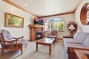 A living room with a fireplace, two armchairs, a sofa, and a television. - Midway Villa with king bedroom, full kitchen, fireplace, pools, and mountain views. (Midway)