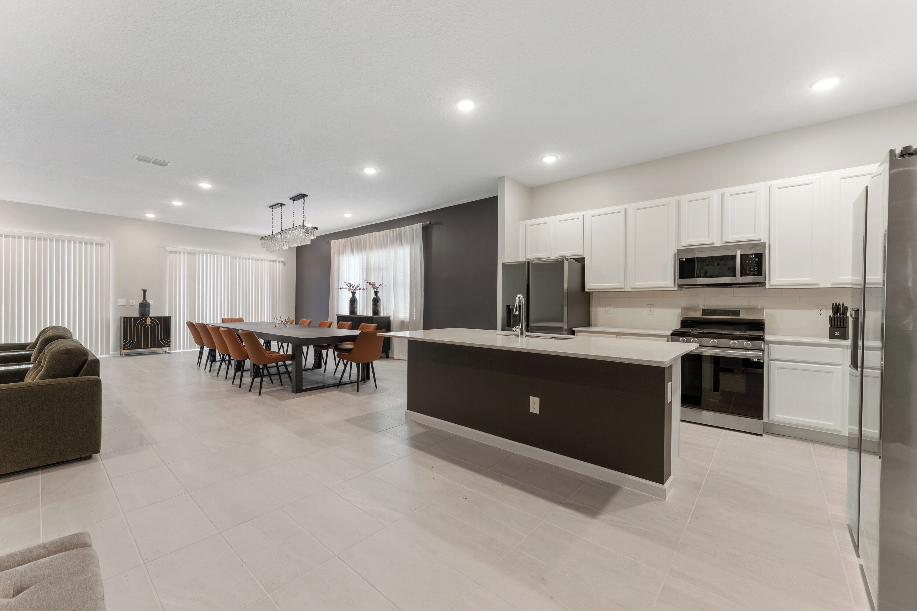 A modern kitchen with a central island, built-in appliances, and a dining area with a table and chairs.