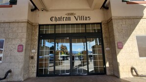 The entrance to Chateau Villas with a sign above the door, a no smoking sign on the wall, and a view of the street through the glass doors. - Midway villa with 1 bedroom, 1 bath, and 2 queen beds at Zermatt Resort. (Midway)