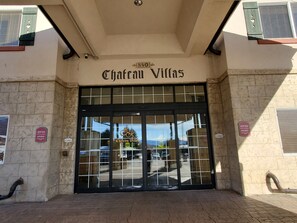 Der Eingang zum Chateau Villas mit einem Schild über der Tür, einem Rauchverbotsschild an der Wand und Blick auf die Straße durch die Glastüren.