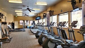 A gym with treadmills, elliptical machines, and a ceiling fan. - Midway villa with 1 bedroom, 1 bath, and 2 queen beds at Zermatt Resort. (Midway)